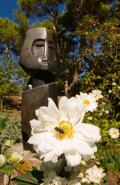 bee on flower in front of stone statue