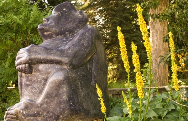 stone sculpture near tree and plants