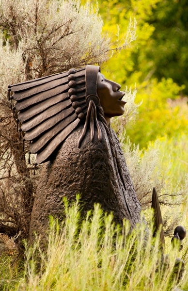 sculpture of person in front of trees.