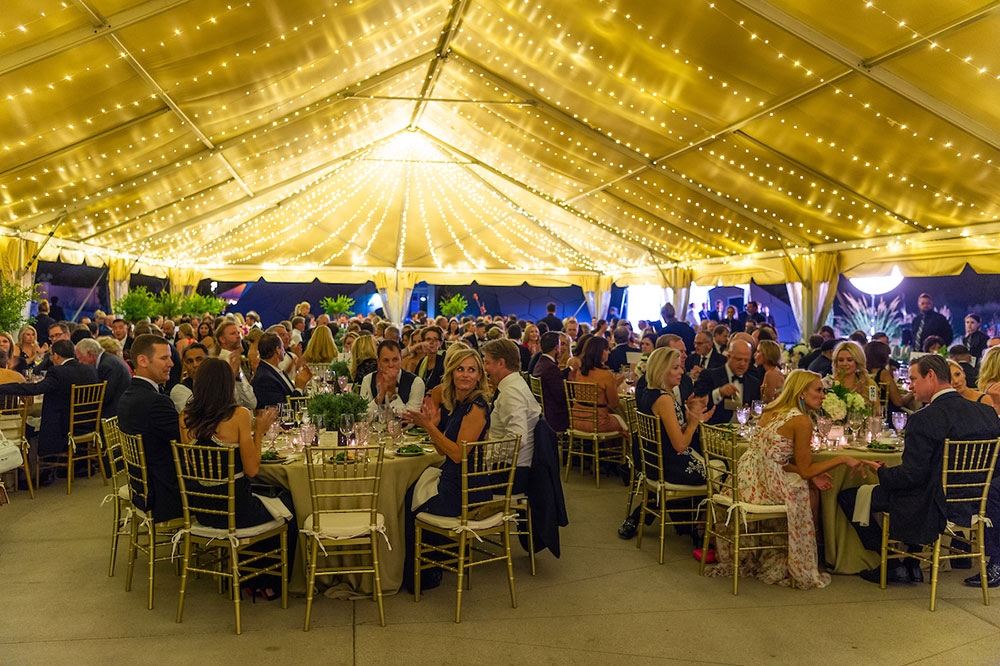 People sitting at tables under the tent at night 