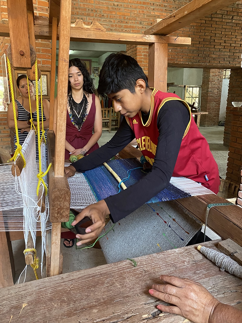 A young boy at a loom, weaving