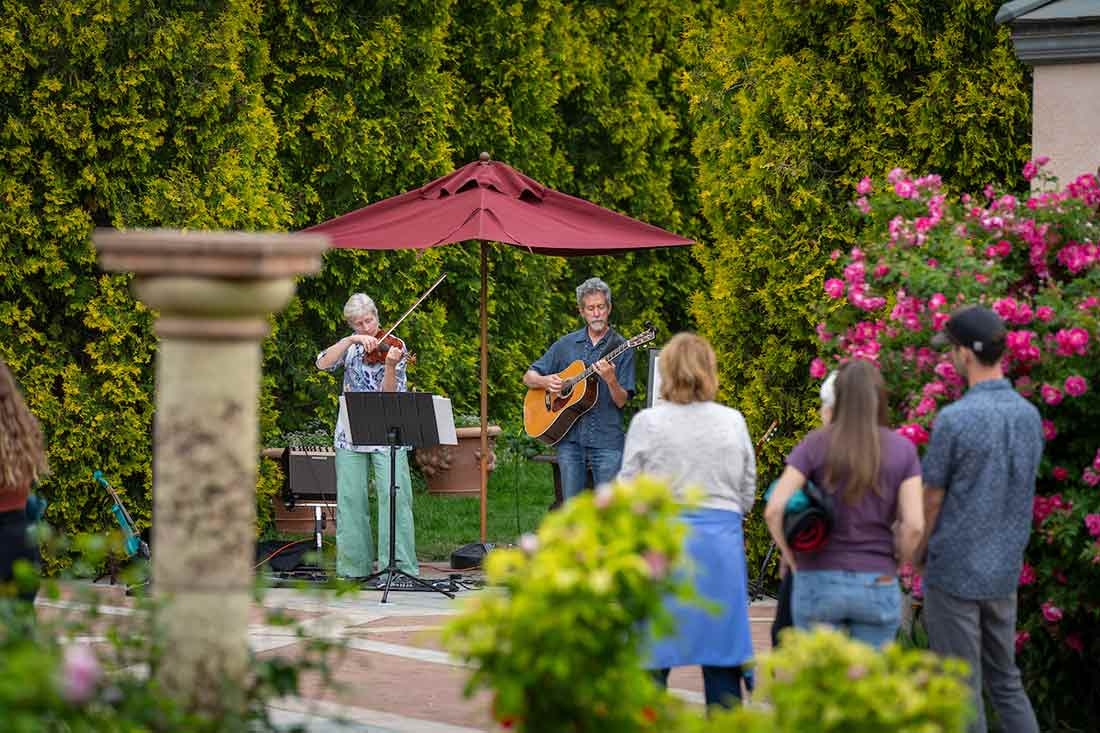 Two people playing a guitar and violin outside at Evenings al Fresco