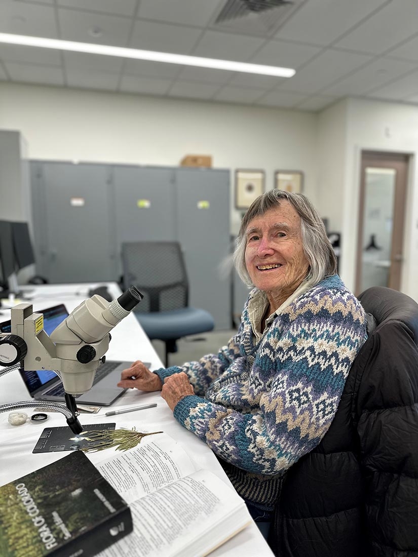 Woman sitting at desk with book and microscope