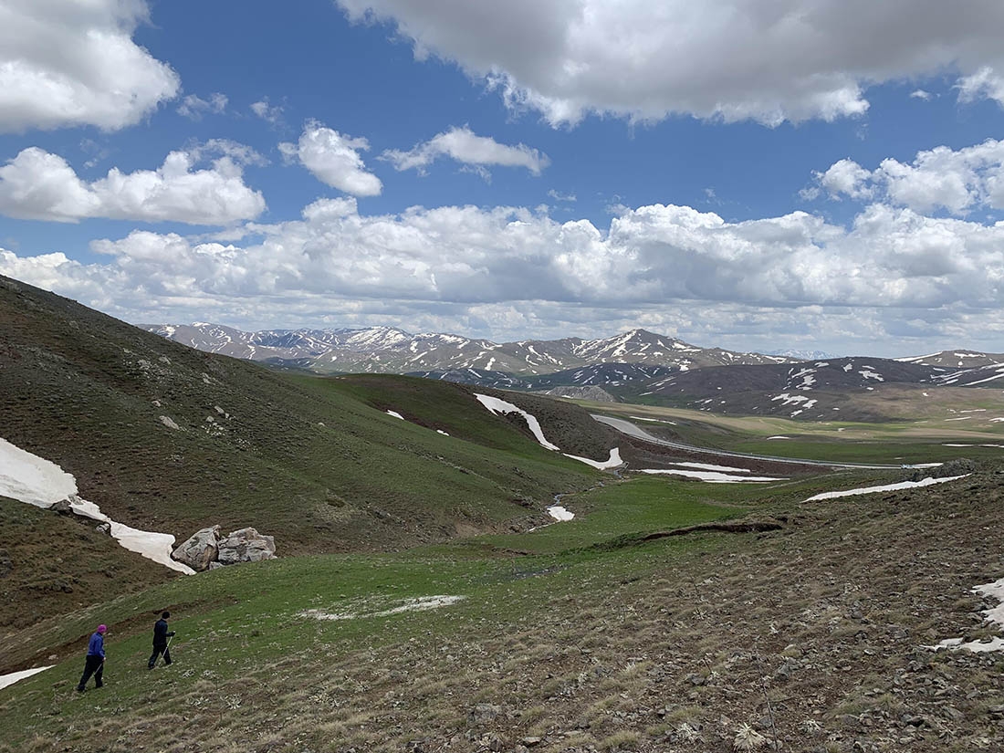 Two people hiking on a windswept mountain plain
