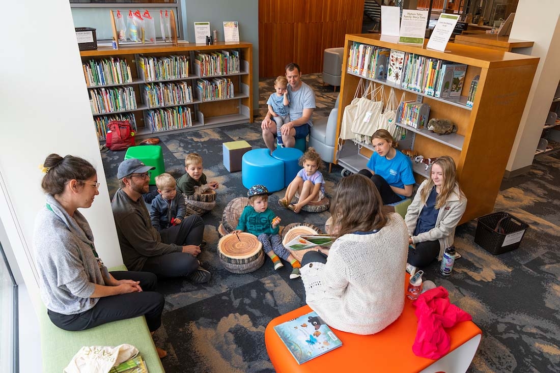 Group of children listening to woman read a children's book