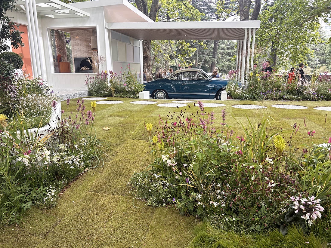 classic car in a carport with tidy flower beds in foreground