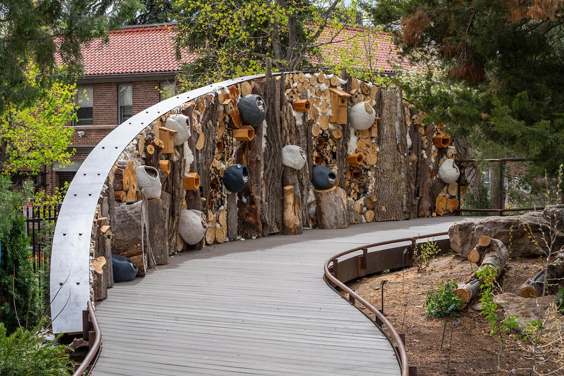 Wooden pathway with a wall of organic pollinator homes