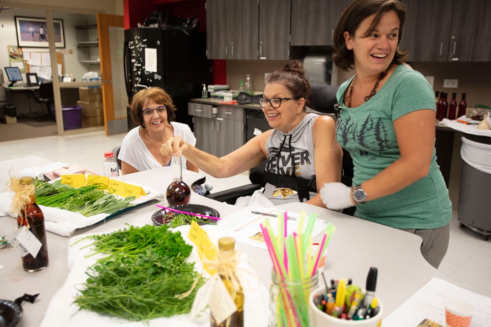 Patients and volunteers at Craig Hospital creating herb infused vinegars during a group horticultural therapy activity.