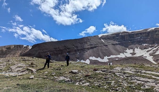 Two scientists at a distance with mountain behind them