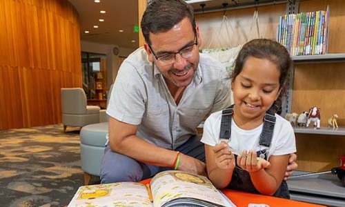 Dad and daughter looking at library book